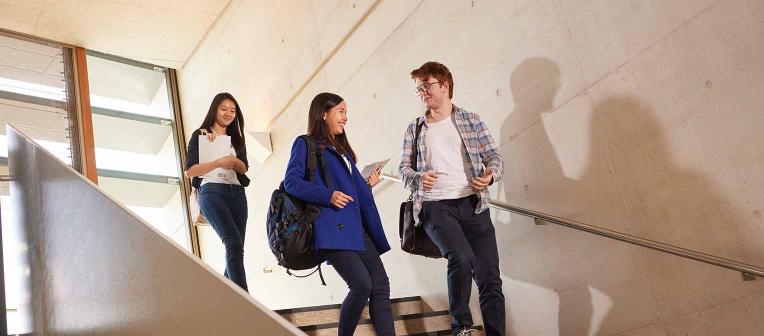 Three students walking down stairs in Advanced Engineering Building.