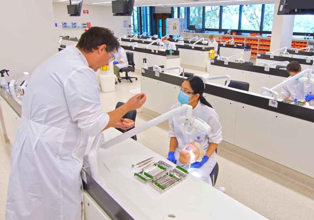 A dentistry student listens to a tutor in the dentistry labs
