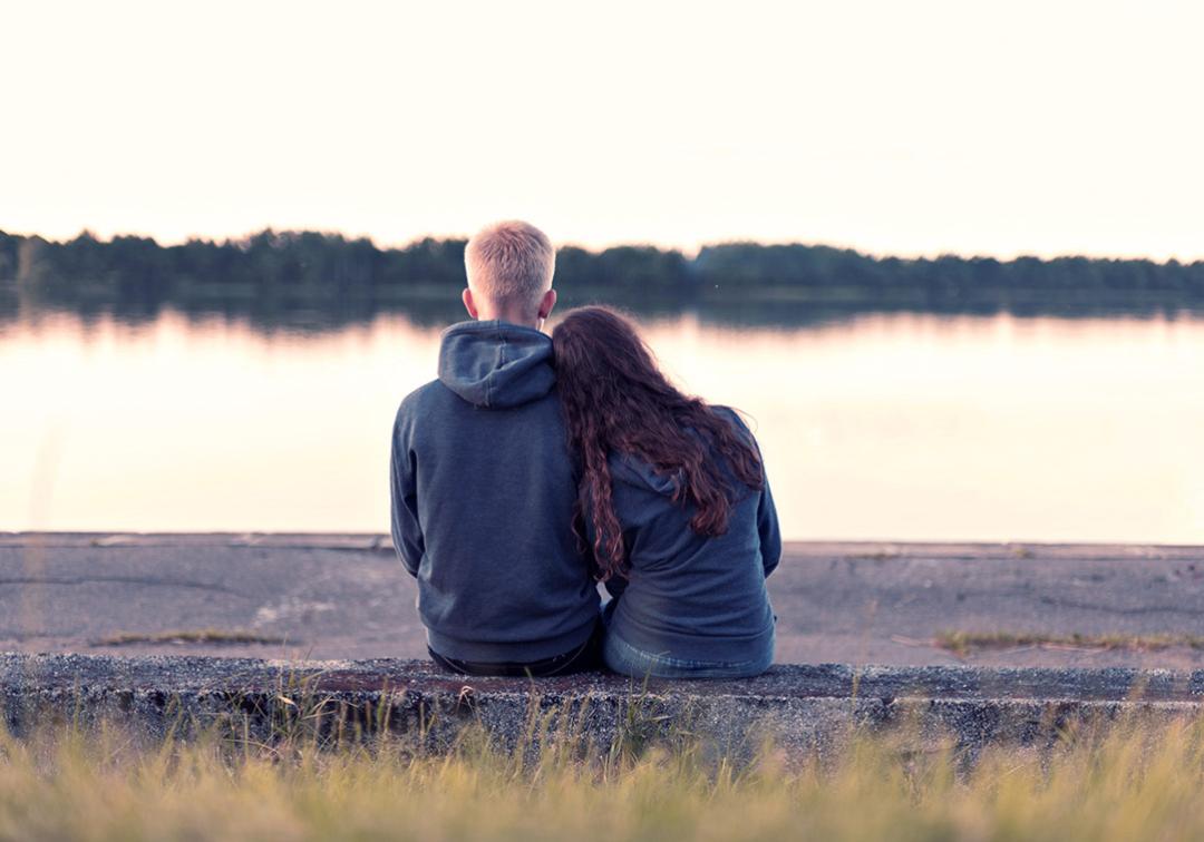 Teenage couple sitting by lake