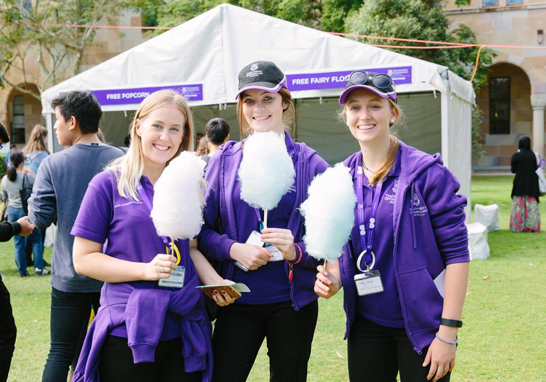Student volunteers holding fairy floss at an event.