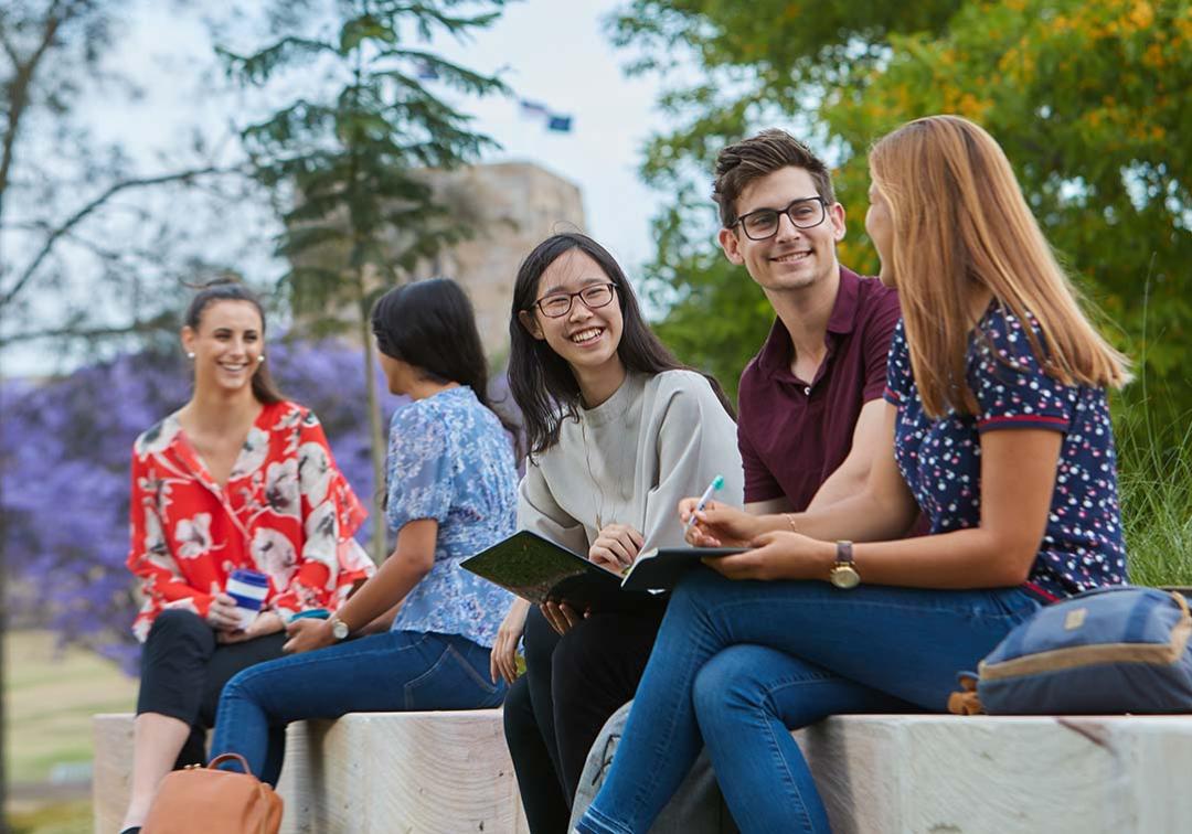 Students sitting on a bench outside at St Lucia campus