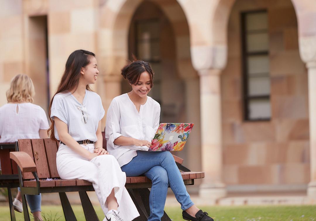 Two young female students sitting on bench in UQ St Lucia Great Court