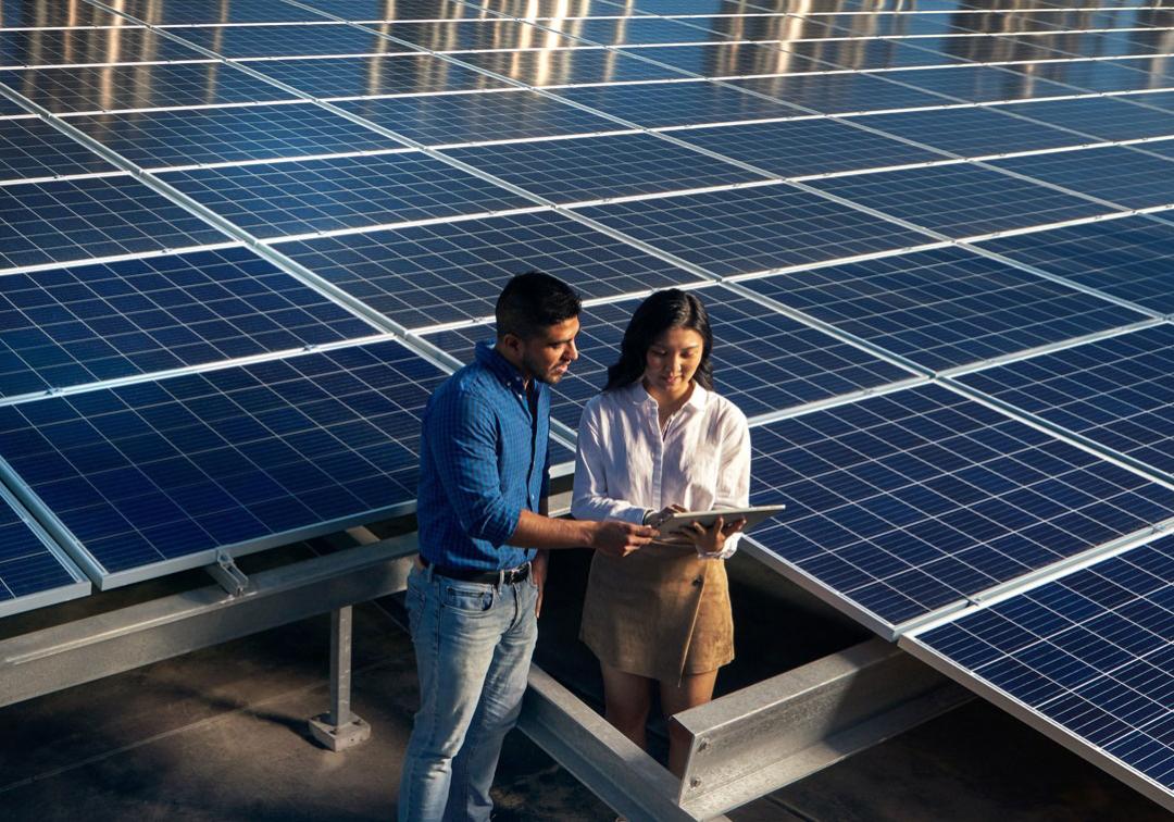 Two people standing in front of solar panels.