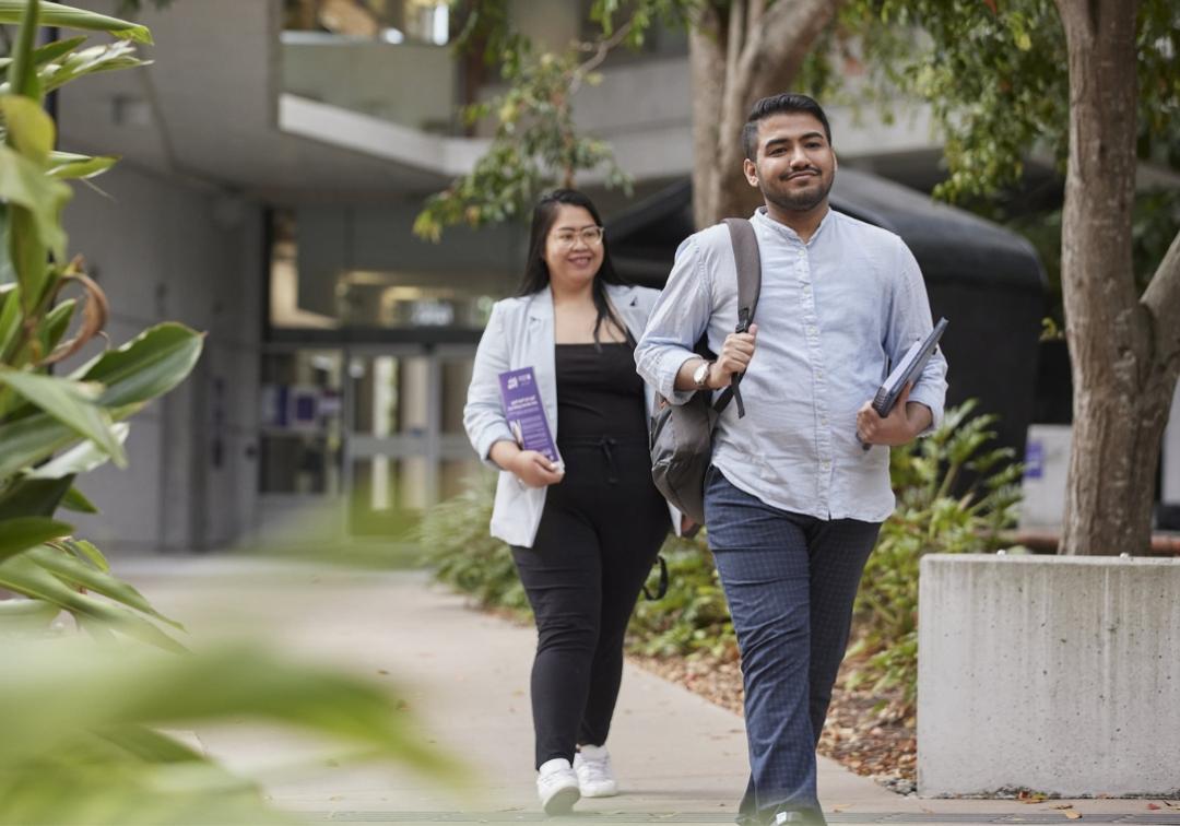 One male and one female student walking on UQ campus