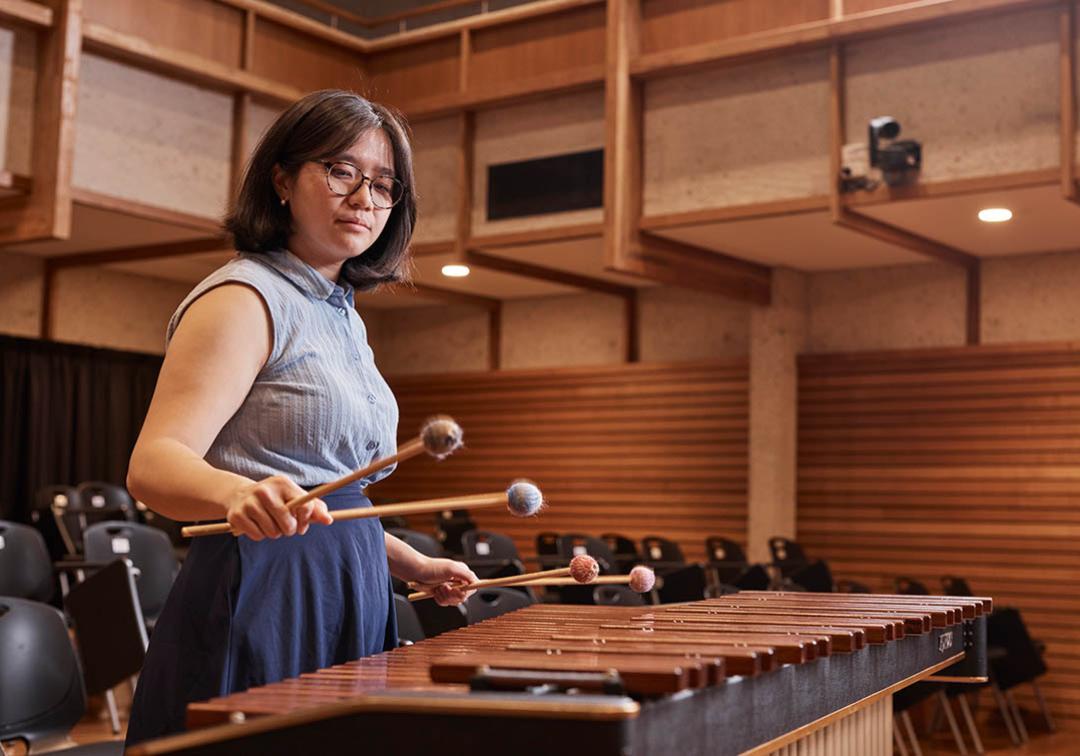 A woman plays a xylophone in a wood panelled room
