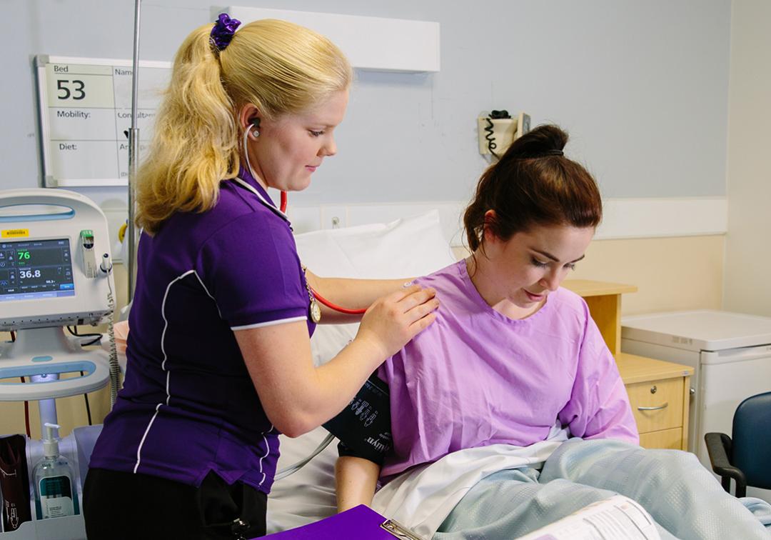 A nursing student checks a patient