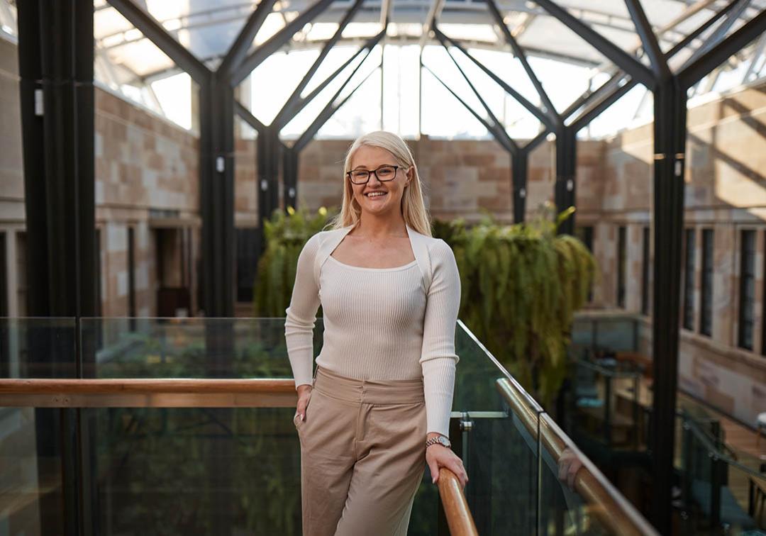 UQ Master of Laws graduate Theresa Shaw stands smiling in a light-filled atrium
