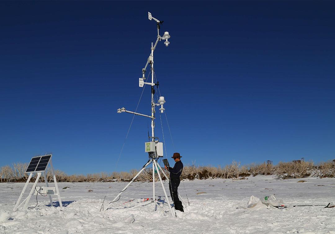 scientist with geological equipment stands in the snow.