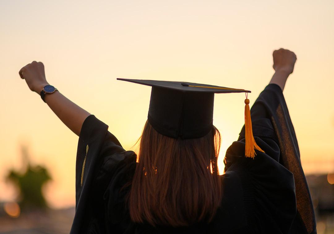 A graduate with their hands in the air
