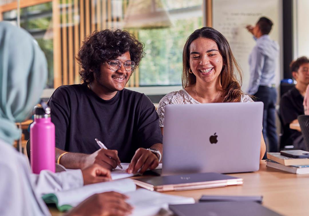 UQ students look at a laptop in a classroom