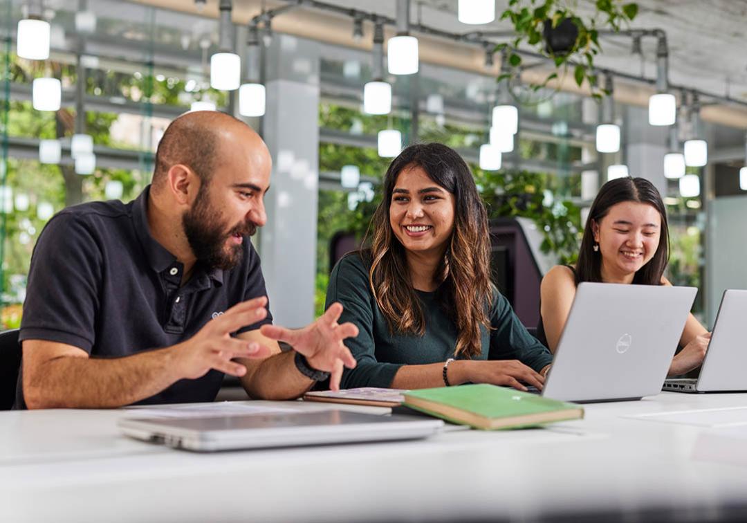 UQ students studying in light-filled classroom at desks with laptops