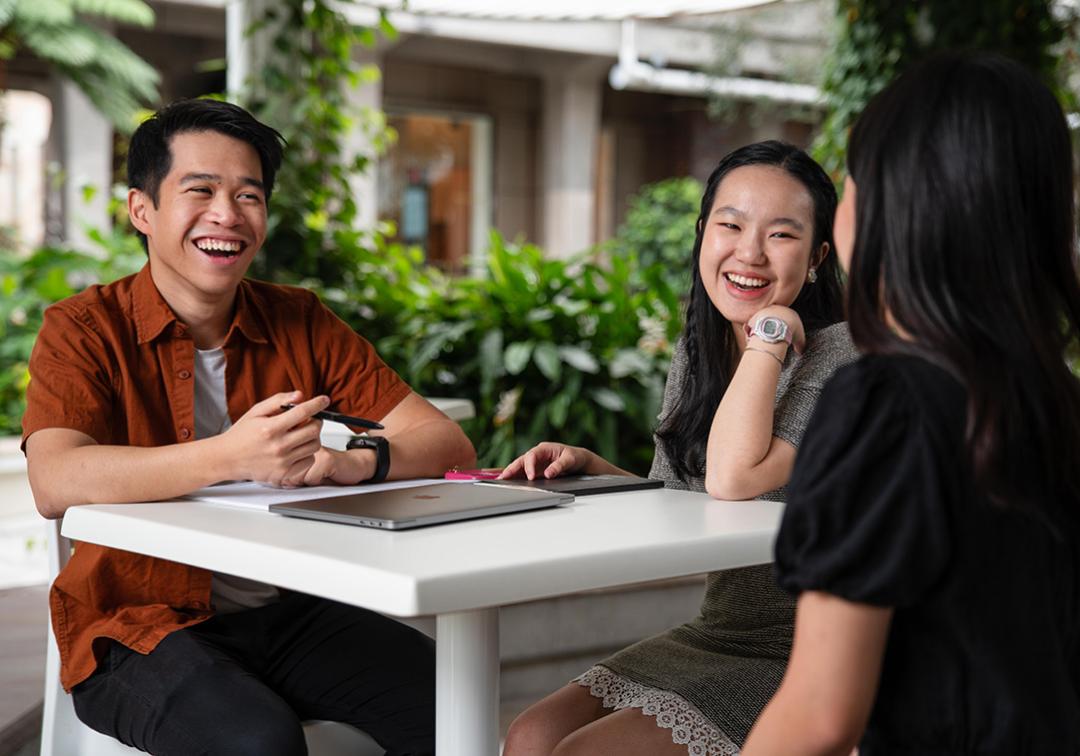 Jeremy Kester Hanani and fellow students chatting around a table outdoors