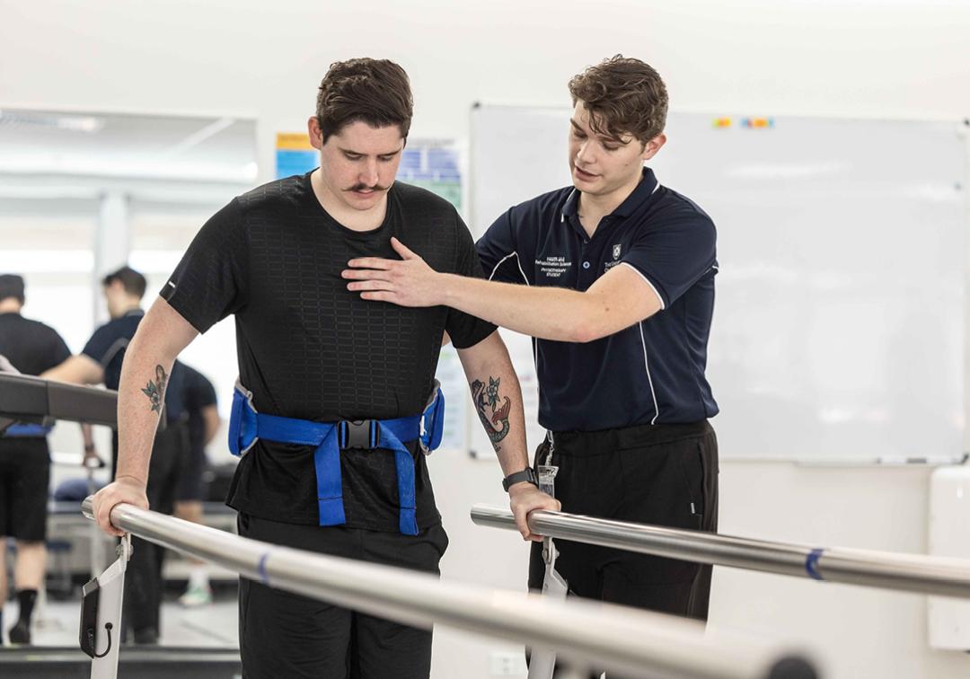 Physiotherapy student assist patient in rehab exercises