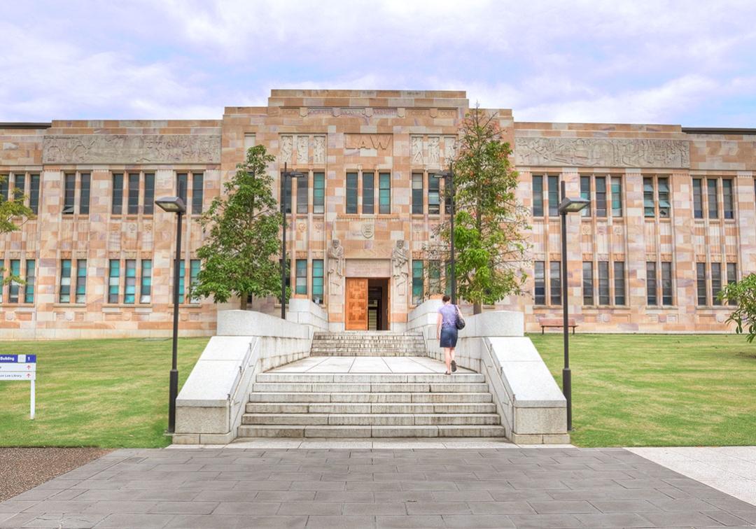 Exterior view of the Forgan Smith Building at the University of Queensland, featuring sandstone and windows.