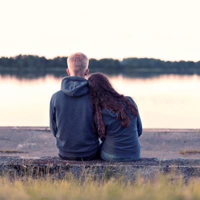 Teenage couple sitting by lake