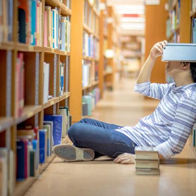 student sitting in library frustrated surrounded by books
