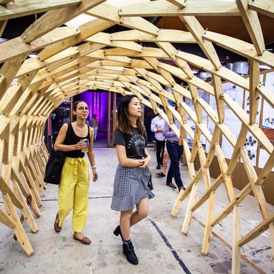 Two students walking under a tessellated wooden archway