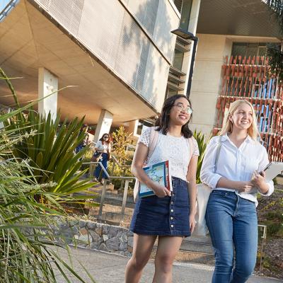 Two young women walking together with books in their hands at UQ's St Lucia campus