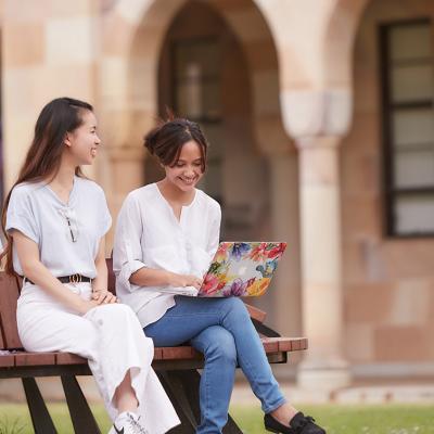 Two young female students sitting on bench in UQ St Lucia Great Court