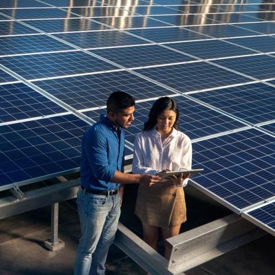 Two people standing in front of solar panels.