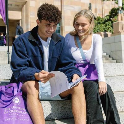 Two teenagers sitting on steps looking at a brochure