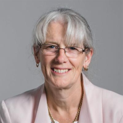 Image of Professor Maureen Hassall, wearing a pink coat and looking straight at the camera.