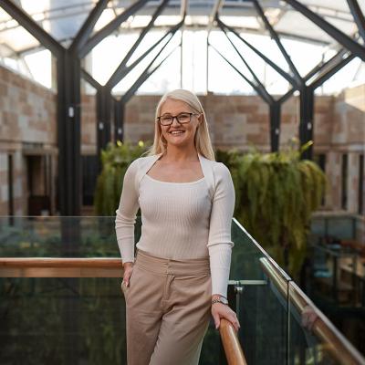 UQ Master of Laws graduate Theresa Shaw stands smiling in a light-filled atrium