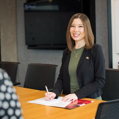 UQ tourism graduate Janita Zhang, sitting at a desk