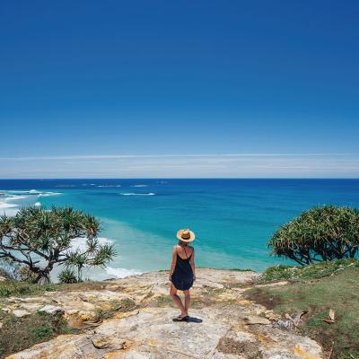 A girl with her back turned overlooking Stradbroke Island on a cliff