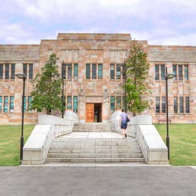 Exterior view of the Forgan Smith Building at the University of Queensland, featuring sandstone and windows.