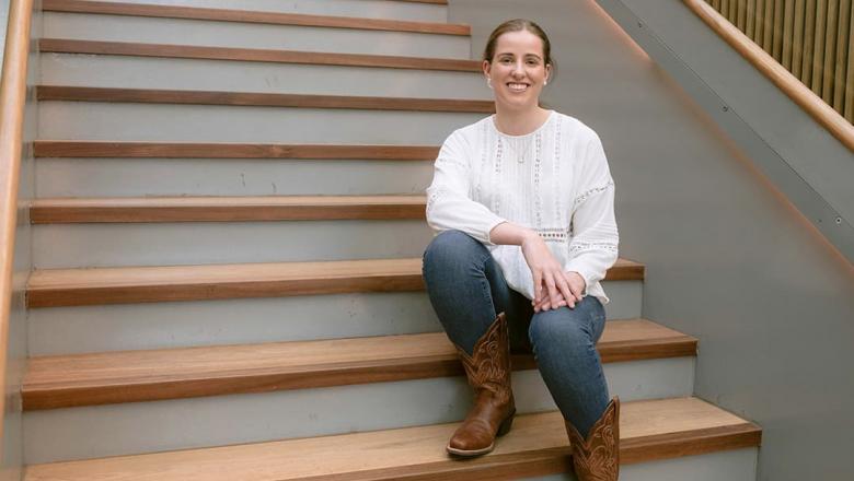 Genevieve Laverty, a UQ agribusiness student, sits smiling on a flight of stairs