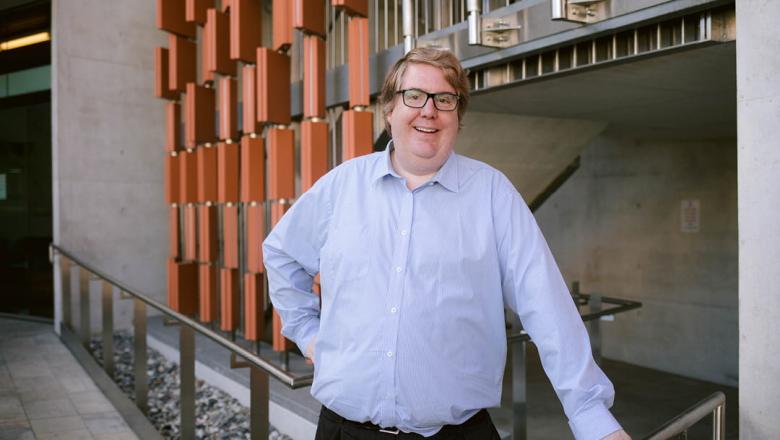 Professor Alastair Blanshard stands smiling in front of an architecturally designed building