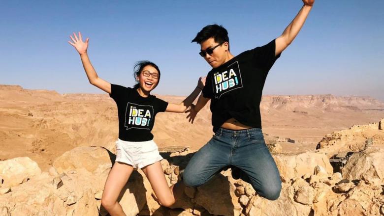 Two students jumping above rocks wearing UQ Idea Hub tshirts