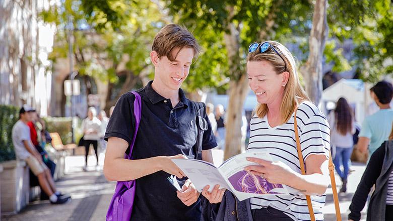 Mother with teenage son look at brochure together at UQ event