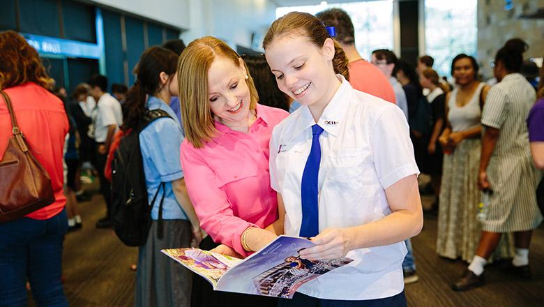 a mother looks at a brochure with her daughter at UQ Open Day