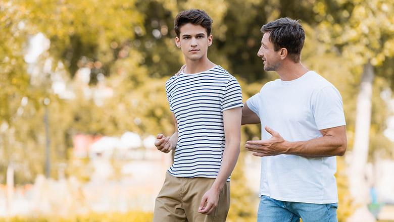 Father walking outside with son and giving advice