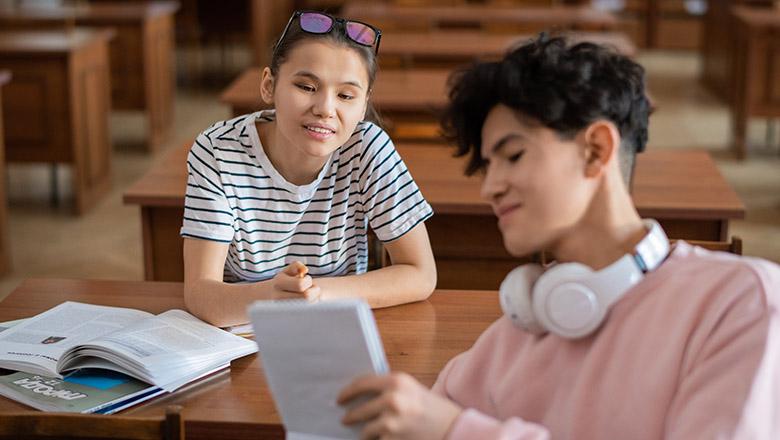 Teenage girl and boy discussing school work