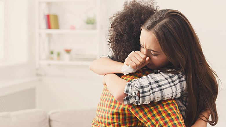 A mother hugs her depressed teenage daughter