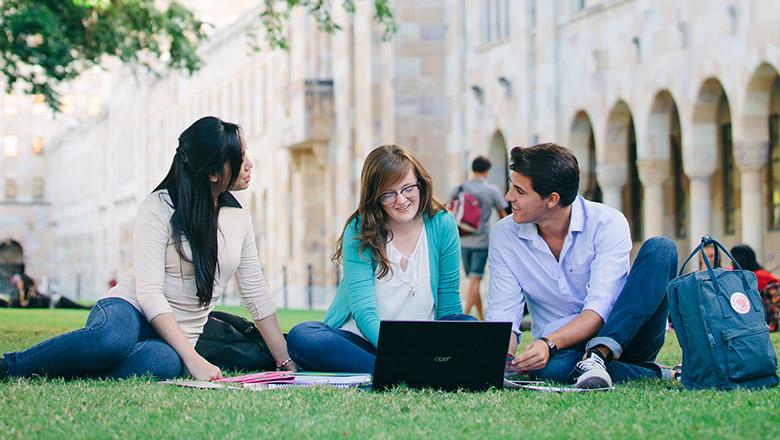 Uni students sit on the grass studying in the Great Court on UQ's St Lucia campus