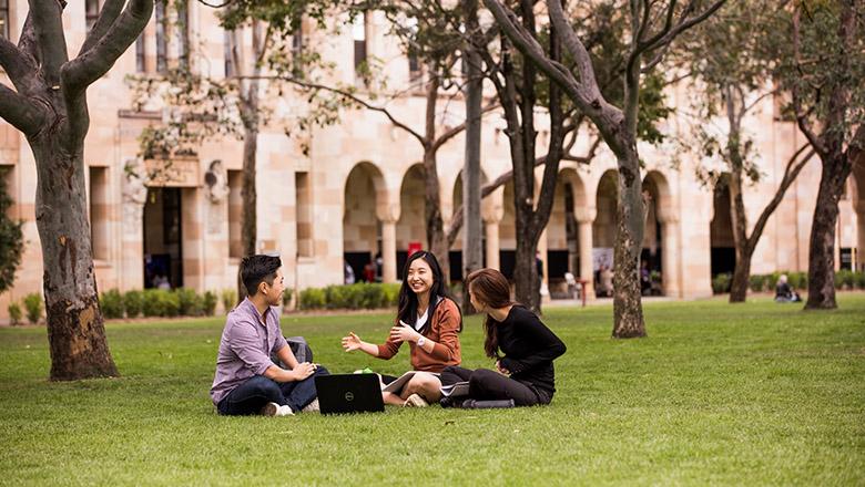 Group of three students sitting talking in great court