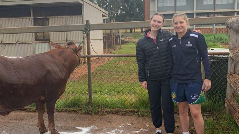 Isabelle Taylor with her friend Meg Muir, standing together in a pen with a cow