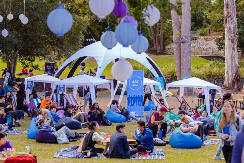 People sitting in groups and beanbags on the lawn at an event.