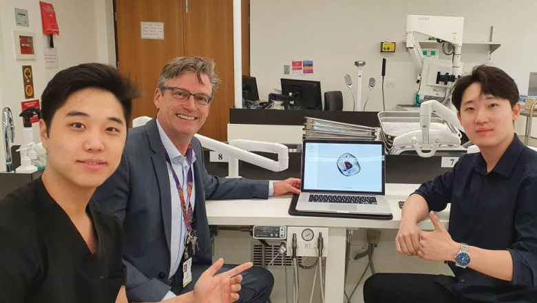 Sean and Ryan Choi sit in a lab with  Prof Ove Peters, pointing at a laptop screen