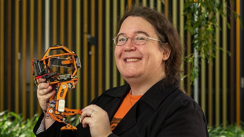 Dr Pauline Pounds is smiling as she holds up a prototype of her Tiny Giant Robot