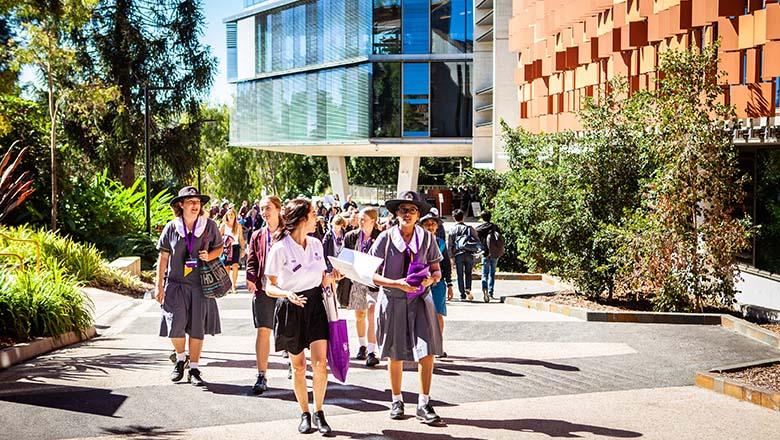 A group of female high school students walk through UQ's St Lucia campus with a guide