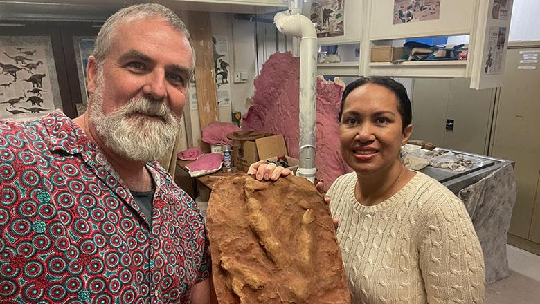 Jaala Ozies and Professor Steven Salisbury stand holding a fossilised dinosaur footprint