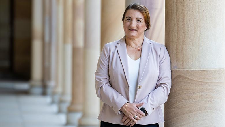 Sandra Micallef, UQ Master of Business Analytics student stands in The Great Court with sandstone pillars in the background