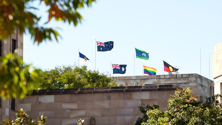 Flags fly atop UQ's Forgan Smith Building on St Lucia campus