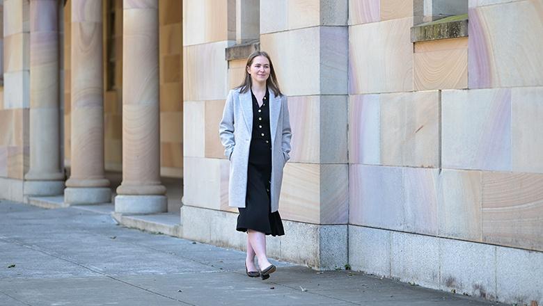 UQ urban planning student Sophia Dow walks through the sandstone cloisters of St Lucia campus