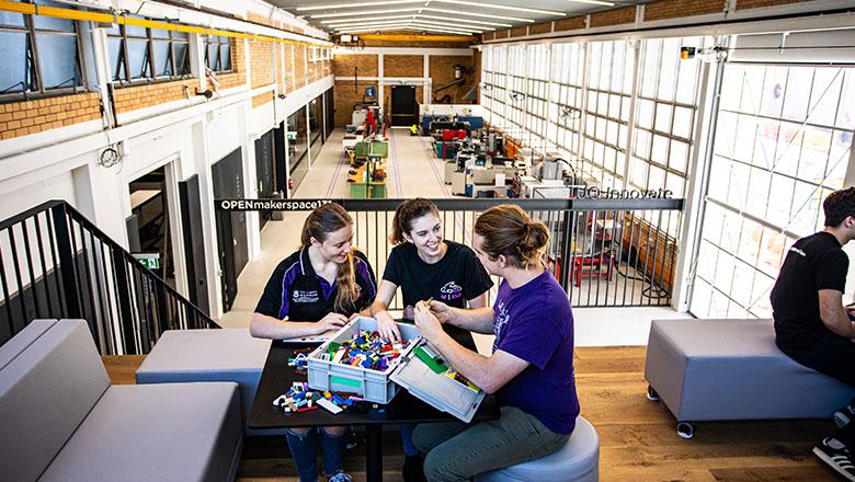 Students sit at a table with a crate of lego on a mezzanine above UQ's MarkerSpace